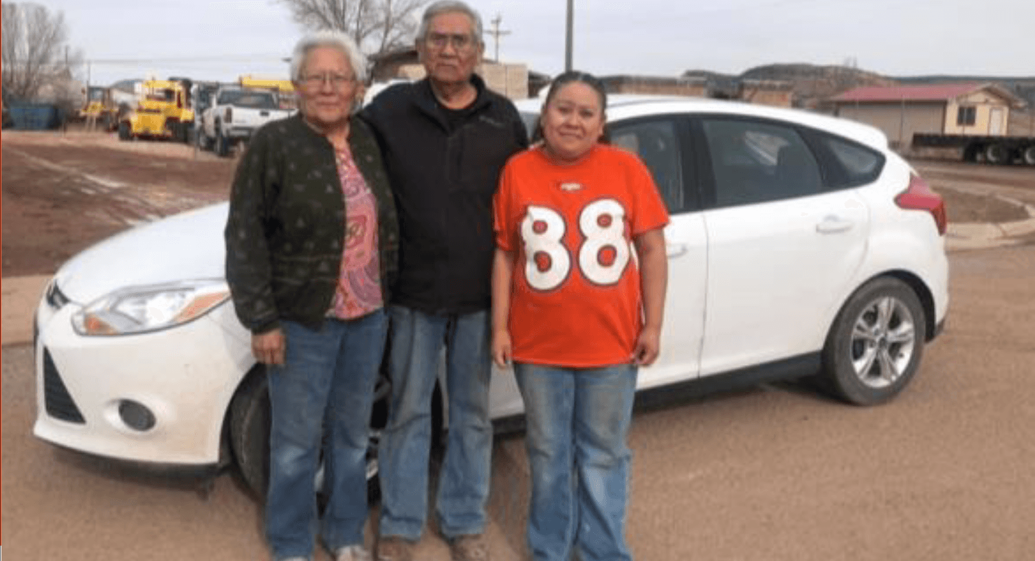 Three community members standing in front of a white Ford Focus