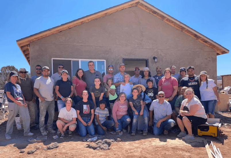 Large group of volunteers gathered in front of the completed home